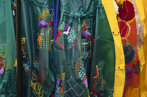 Peça de arte da coleção Geleia Geral de Ana Clara Watanabe: diversos pedaços de tecidos coloridos costurados a uma grande capa verde.